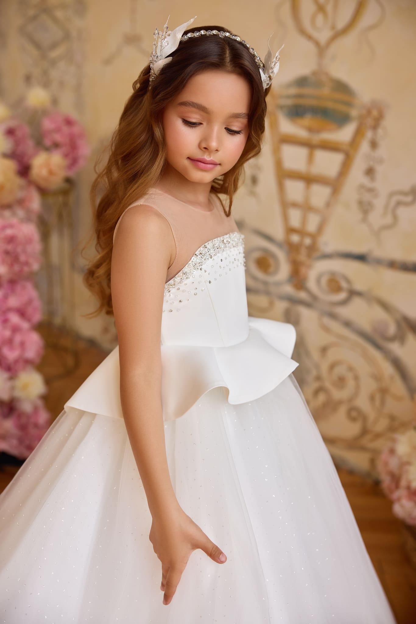 Detailed side view of the white satin and ivory tulle girl's gown, showcasing delicate pearl embellishments and fine mesh neckline.
