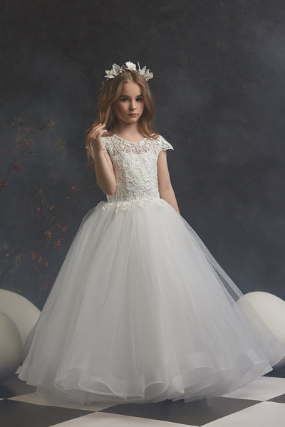 Young girl in Lace and Pearls Ivory Flowergirl Dress standing against a dark background