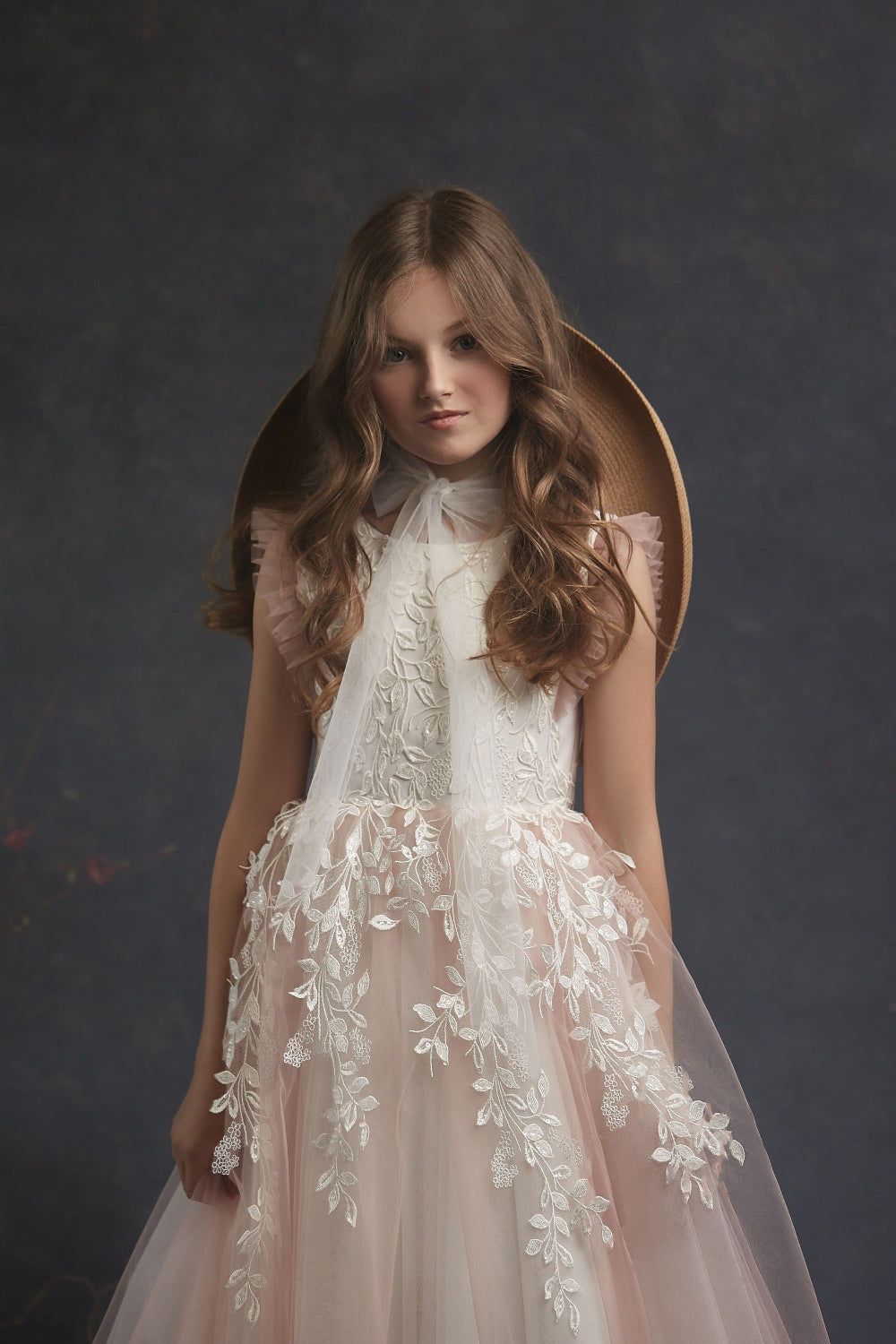 Girl wearing Leaf Pattern Blush Flower Girl Dress floral dress against a dark background