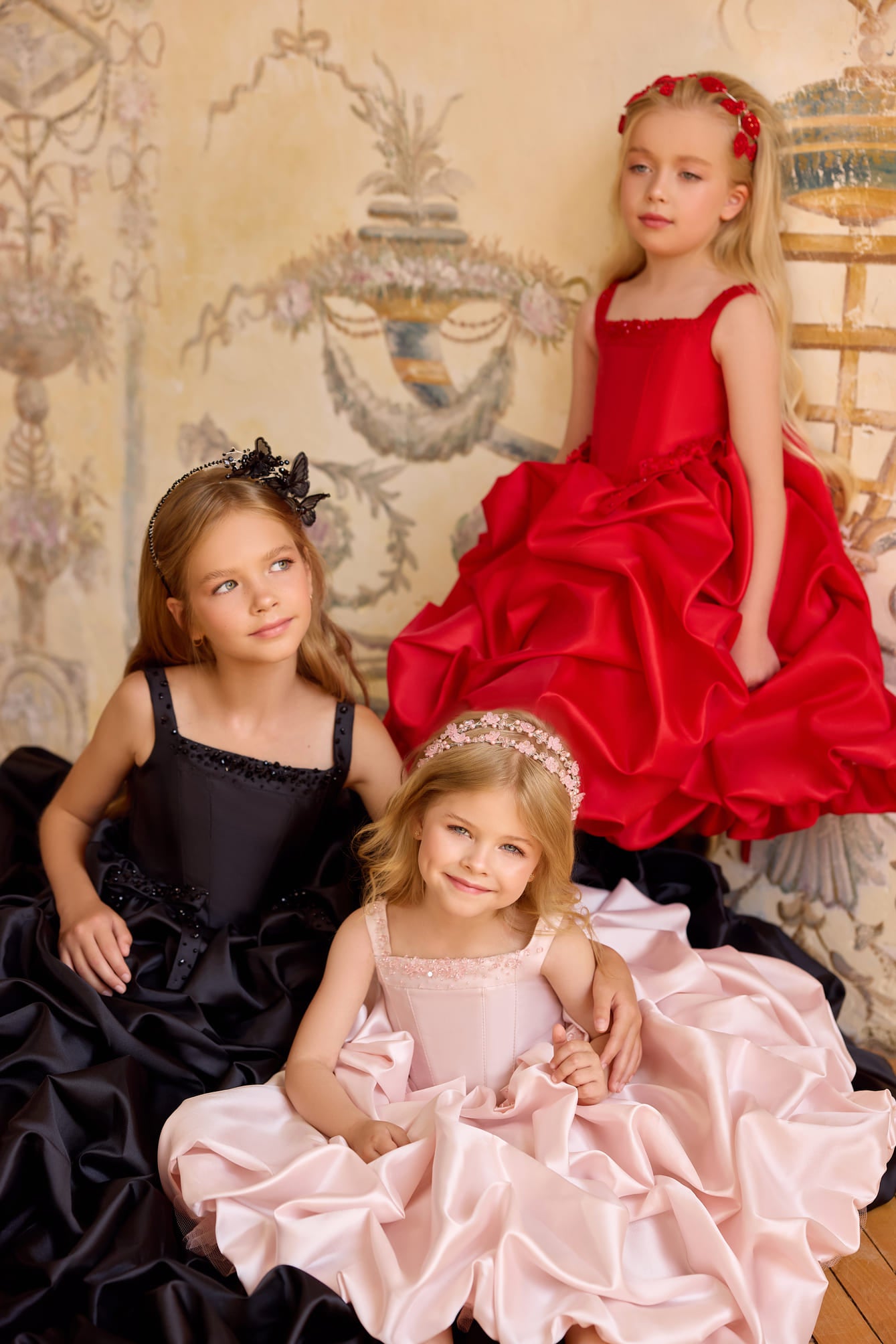 Luxury girls couture ball gowns in black, blush pink, and red with dramatic satin ruffle skirts and crystal embellished bodices