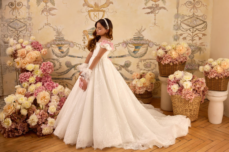 Girl in ivory lace communion gown with blush bows and train