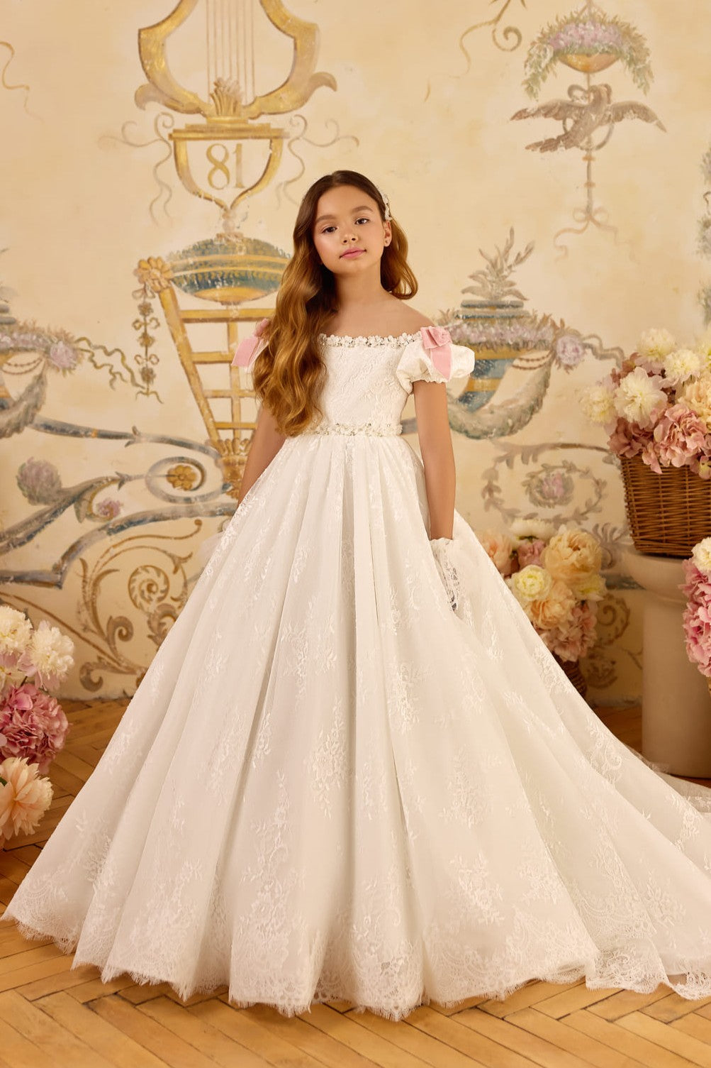 Girl in ivory lace communion gown with blush bows and train