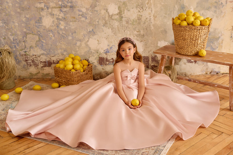 Girl in blush pink satin gown sitting with full ball gown skirt