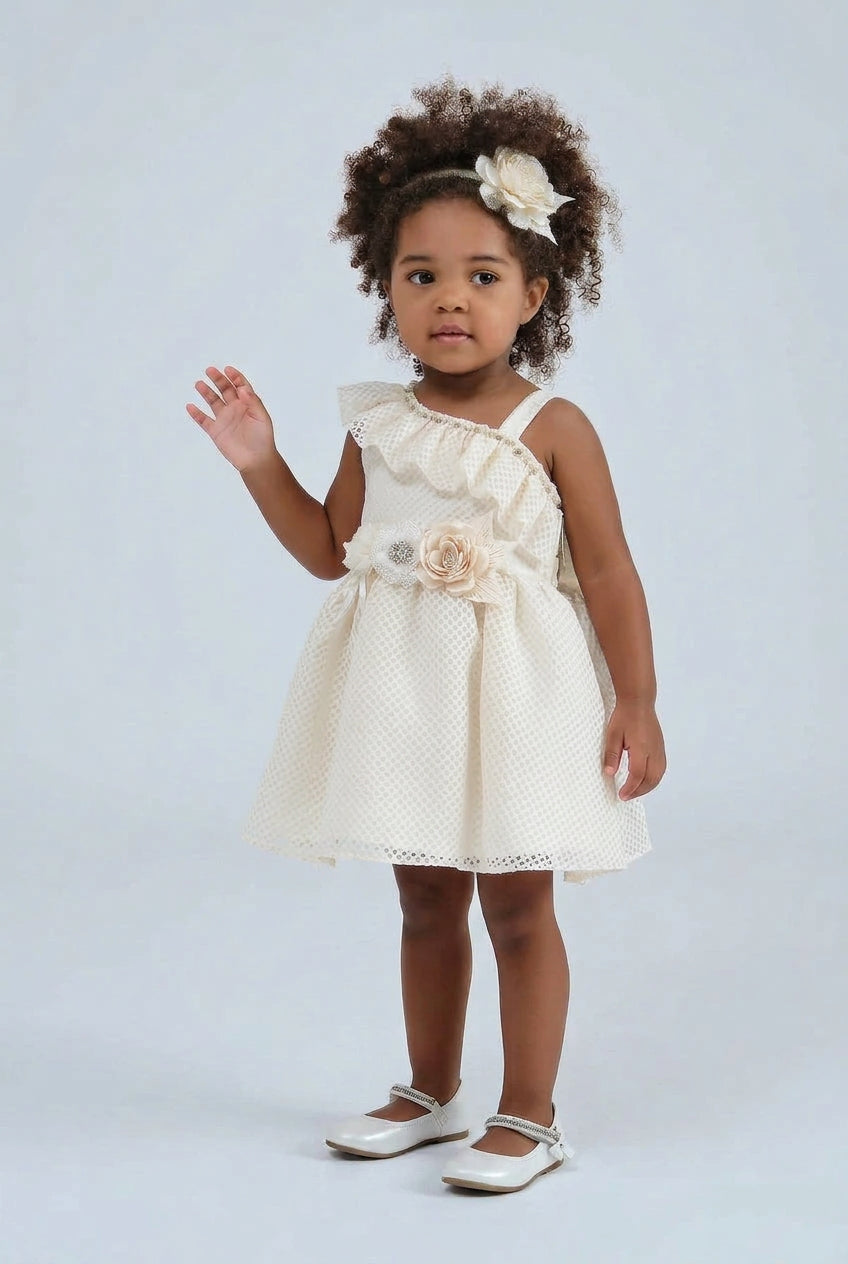Toddler wearing the ruffle shoulder first birthday dress with flower corsage and headband, ivory colourway shown - Mia Bambina Boutique