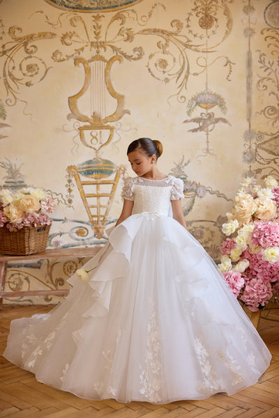 Girl wearing lace Communion dress with puff sleeves and bow