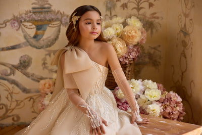 Champagne one-shoulder Communion dress with oversized bow and beaded details