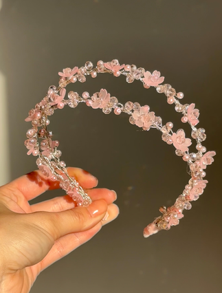 Hand holding pink floral double headband with pearls and crystals