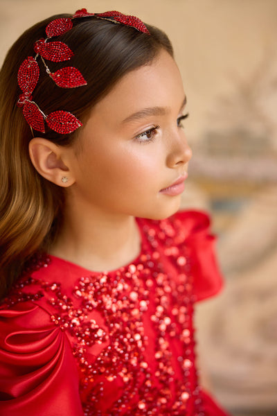 Girl wearing red crystal leaf communion hairpiece with matching dress