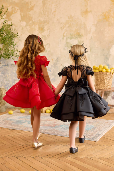 Back view of red and black sequin bow girls dresses with oversized bows