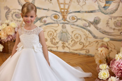 Girl wearing pearl embellished Communion dress with bow waist