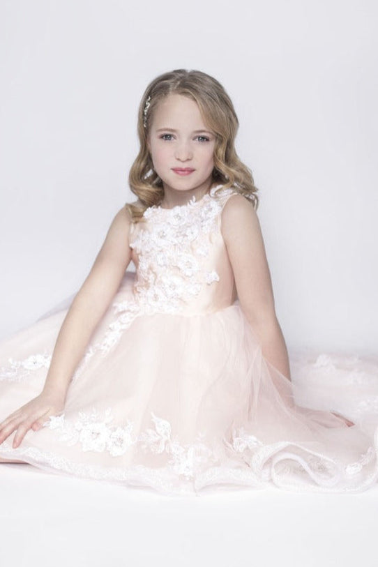 Young girl in a pink floral dress sitting on a white background