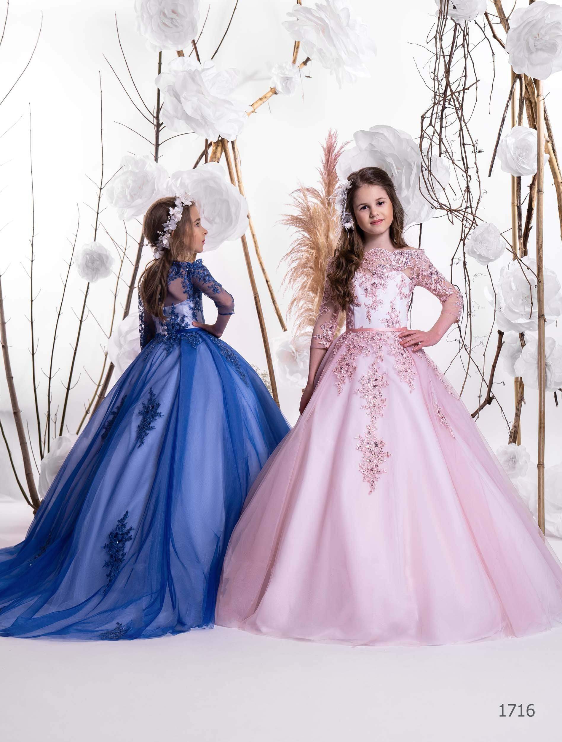Two girls in embroidered flower girl gowns – one in royal blue, one in pink – with long tulle skirts and sheer sleeves.